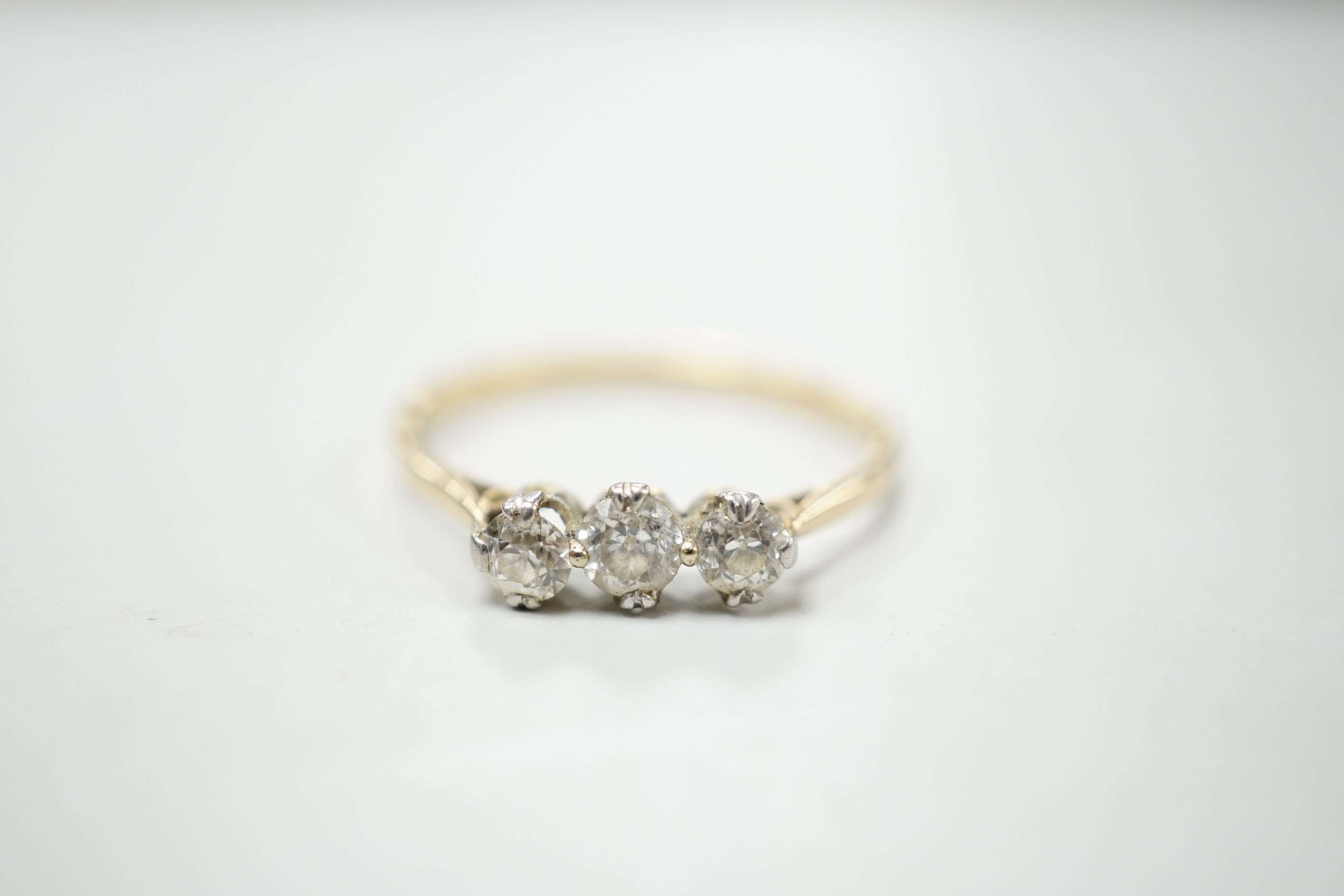 A yellow metal and three stone diamond set ring, size S/T, gross weight 2.1 grams.